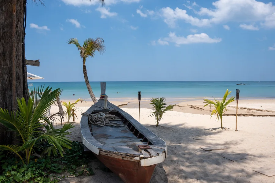 A longtail boat on the beach — Bang Tao Beach, Phuket · The Title Cocoon